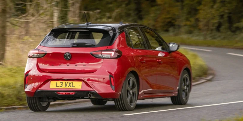 Brand new red Vauxhall Corsa going around a corner